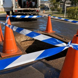 Blue and white barricade tape ringing a water main works area on a suburban street